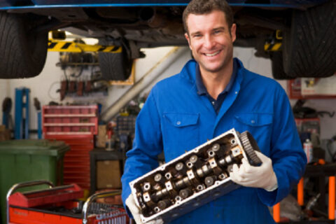 man smiling with gear part in hand