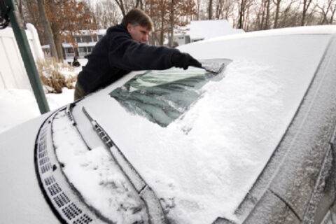 man clearing snow from his car