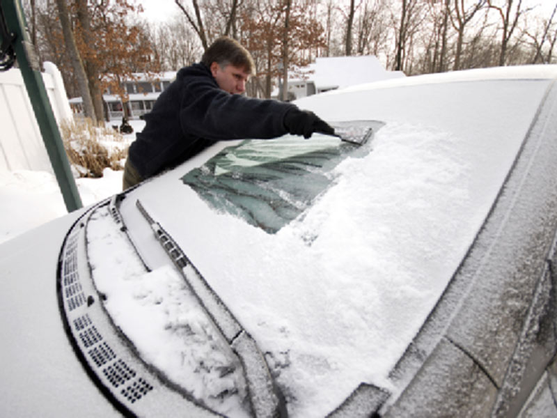 man clearing snow from his car