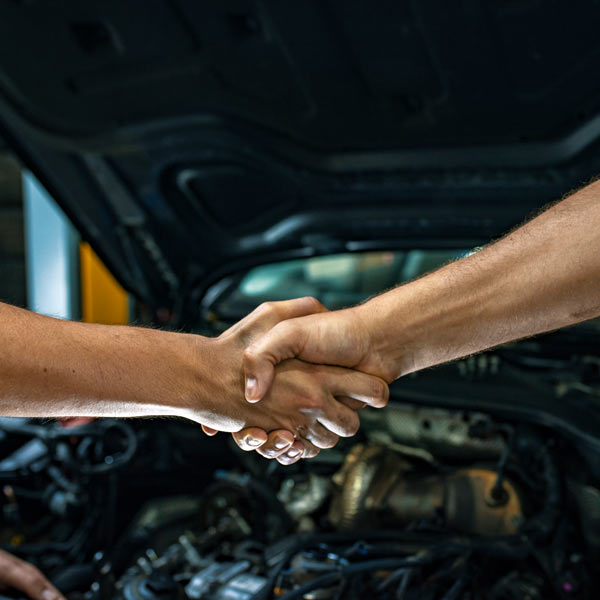 handshake in front of car engine