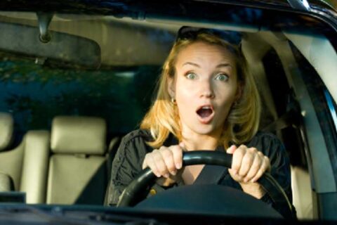 shocked reaction of a woman while driving a car