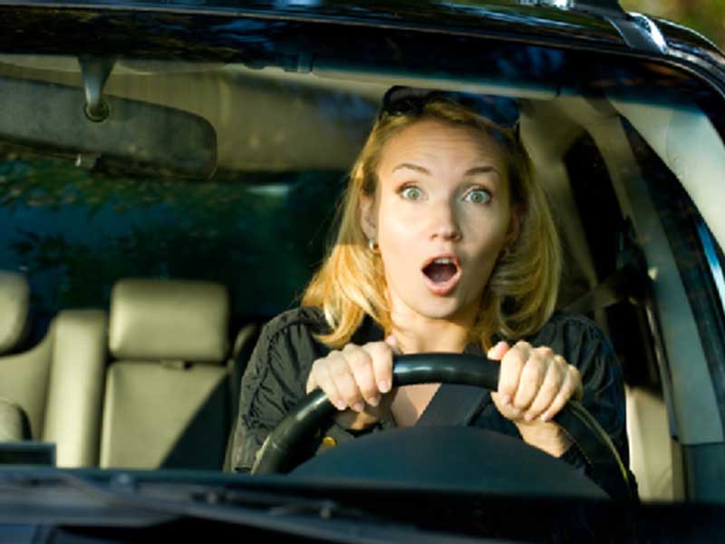 shocked reaction of a woman while driving a car