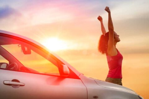 women enjoying sunset standing beside her car