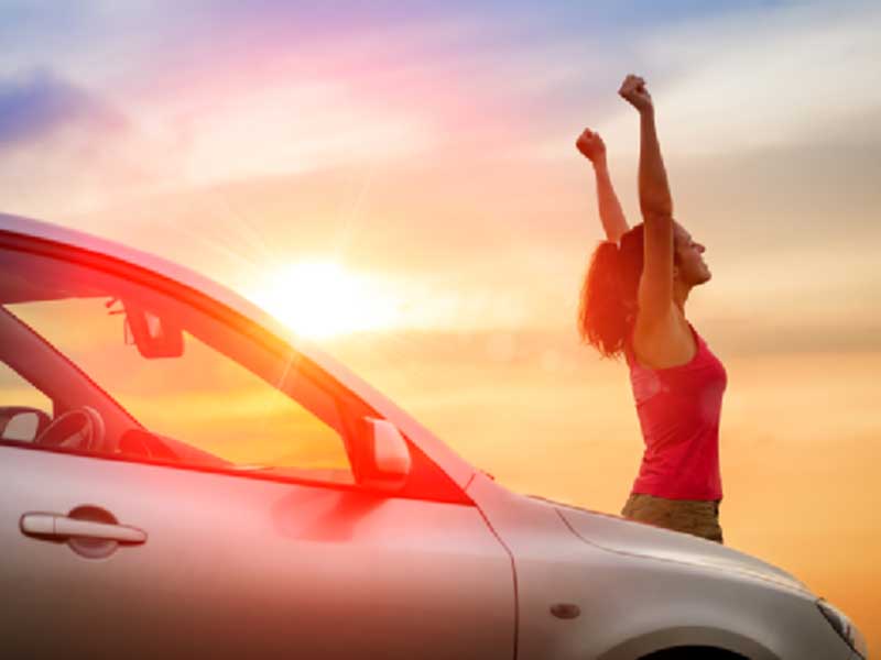 women enjoying sunset standing beside her car